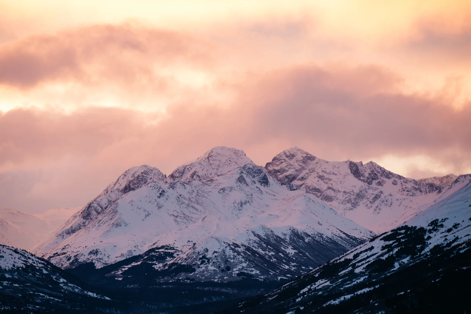 Snow-covered mountain peaks beneath a warm sunset sky