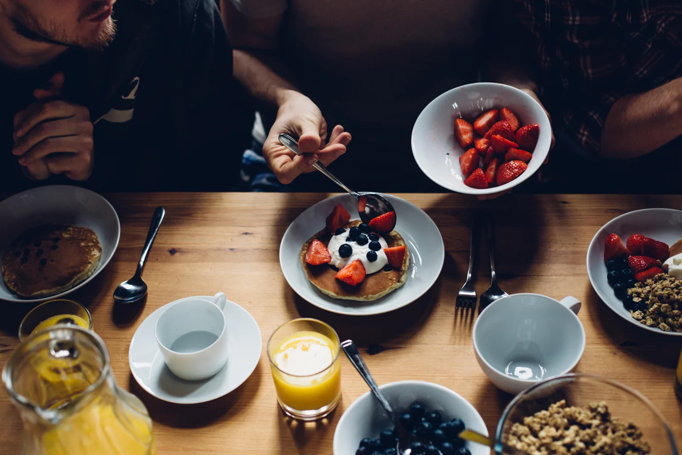 People gathered around a table of breakfast food and coffee